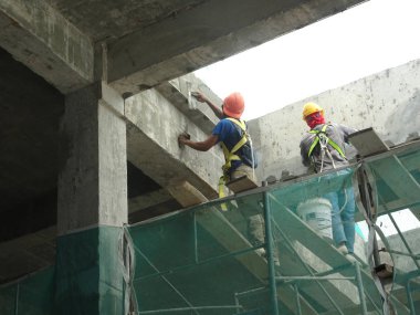 Kuala Lumpur, Malezya-23 Ağustos 2018: çimento alçı kullanarak inşaat işçileri tarafından sıvalı tuğla duvar. İskele geçici evreleme olarak yükseklikte çalışırdım. Kötü olmasını önlemek için uygun güvenlik dişli giyiyor.  