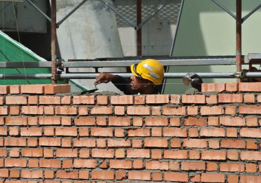 JOHOR, MALAYSIA -AĞUSTOS 05, 2016: İnşaat alanında inşaat duvarları oluşturmak için tuğla döşeyen tuğla ustası. 