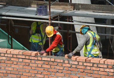 JOHOR, MALAYSIA -AĞUSTOS 05, 2016: İnşaat alanında inşaat duvarları oluşturmak için tuğla döşeyen tuğla ustası. 