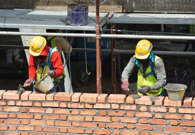 JOHOR, MALAYSIA -AĞUSTOS 05, 2016: İnşaat alanında inşaat duvarları oluşturmak için tuğla döşeyen tuğla ustası. 