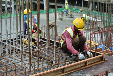 KUALA LUMPUR, MALAYSIA -JUNE 27, 2016: Construction workers fabricating steel reinforcement bar at the construction site in. The reinforcement bar was ties together using tiny wire.