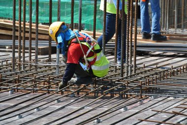 KUALA LUMPUR, MALAYSIA -JUNE 27, 2016: Construction workers fabricating steel reinforcement bar at the construction site in. The reinforcement bar was ties together using tiny wire.