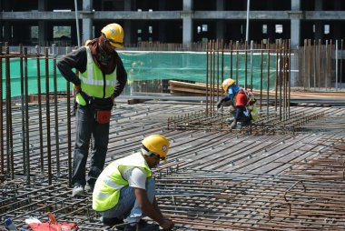 KUALA LUMPUR, MALAYSIA -JUNE 27, 2016: Construction workers fabricating steel reinforcement bar at the construction site in. The reinforcement bar was ties together using tiny wire.
