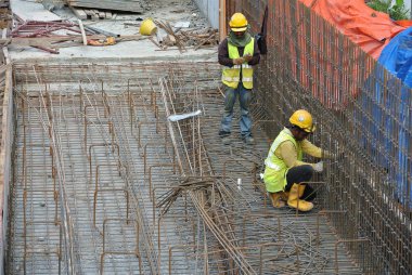KUALA LUMPUR, MALAYSIA -JUNE 27, 2016: Construction workers fabricating steel reinforcement bar at the construction site in. The reinforcement bar was ties together using tiny wire.