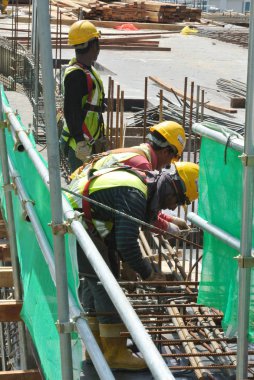 KUALA LUMPUR, MALAYSIA -JUNE 27, 2016: Construction workers fabricating steel reinforcement bar at the construction site in. The reinforcement bar was ties together using tiny wire.