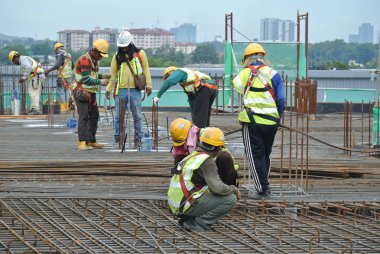 KUALA LUMPUR, MALAYSIA -JUNE 27, 2016: Construction workers fabricating steel reinforcement bar at the construction site in. The reinforcement bar was ties together using tiny wire.