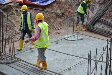 KUALA LUMPUR, MALAYSIA -JUNE 27, 2016: Construction workers fabricating steel reinforcement bar at the construction site in. The reinforcement bar was ties together using tiny wire.