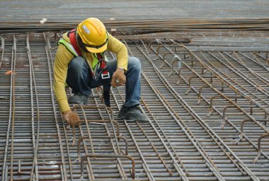 KUALA LUMPUR, MALAYSIA -JUNE 27, 2016: Construction workers fabricating steel reinforcement bar at the construction site in. The reinforcement bar was ties together using tiny wire.