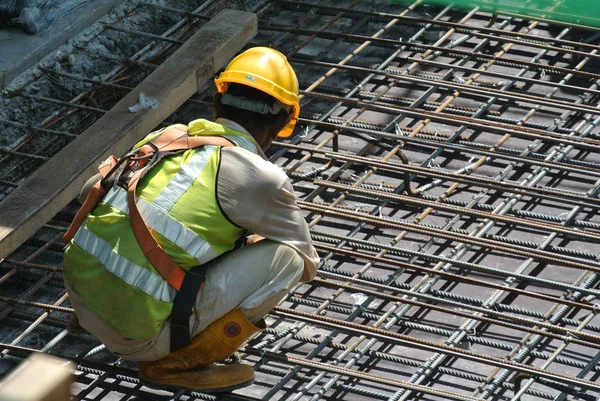 KUALA LUMPUR, MALAYSIA -JUNE 27, 2016: Construction workers fabricating steel reinforcement bar at the construction site in. The reinforcement bar was ties together using tiny wire.