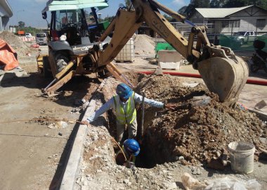 Kuala Lumpur, Malezya-02 Mayıs 2017: yeraltı yarar kablo ve hizmetlerini yüklemek işçi boru inşaat sahasında sığ siperlerde. Tarak makine tarafından kazılan siperleri. 