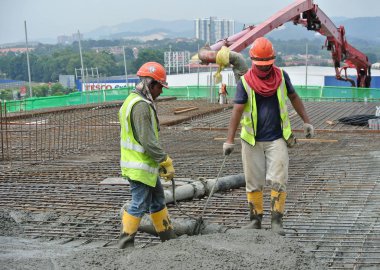 Selangor, Malezya-01 Ağustos 2016: grup inşaat sahasında kereste formu işe Vinç kovası kullanarak ıslak beton dökme inşaat işçileri.  