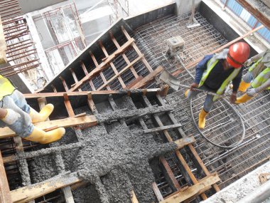 Selangor, Malezya-01 Ağustos 2016: grup inşaat sahasında kereste formu işe Vinç kovası kullanarak ıslak beton dökme inşaat işçileri.  