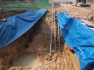 İnşaat alanında büyük plastik levha kullanarak geçici yamaç korumayı. Toprak profil tutmak ve yağmur yağdığında toprak erozyonu önlemek olduğunu.