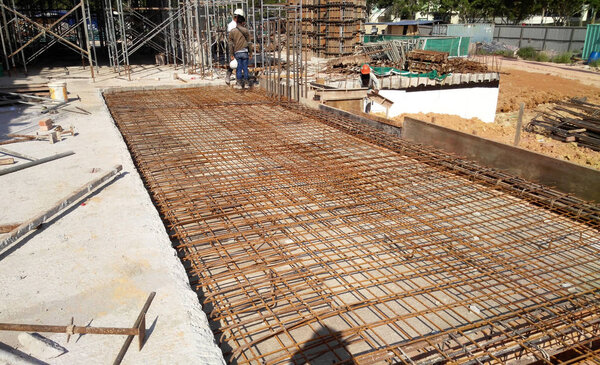 KUALA LUMPUR, MALAYSIA -MARCH 03, 2019: Floor slab and beam reinforcement bar under fabrication at the construction site by workers. It is tied together using tiny wires. 