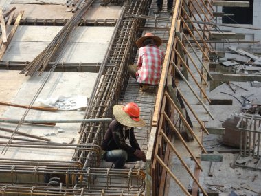 Kuala Lumpur, Malezya -Mart 29, 2010: İnşaat işçileri inşaat alanında takviye beton oluşturmak için çelik takviye çubuğu imal. Küçük kabloları kullanarak birbirine bağladılar.