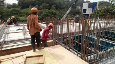 Kuala Lumpur, Malezya -Mart 29, 2010: İnşaat işçileri inşaat alanında takviye beton oluşturmak için çelik takviye çubuğu imal. Küçük kabloları kullanarak birbirine bağladılar.