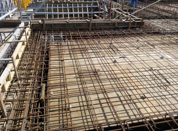 KUALA LUMPUR, MALAYSIA -MARCH 08, 2019: Floor slab and beam reinforcement bar under fabrication at the construction site by workers. It is tied together using tiny wires. 