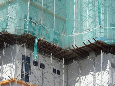 Kuala Lumpur, Malezya -16 Temmuz 2019: Yüksek katlı bina inşaatı sırasında binanın dış cephesinde platform ve güvenlik ağlarını yakalayın. Bireyleri ve malları düşen enkazlardan korur. 