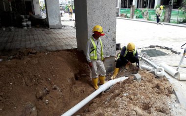 Kuala Lumpur, Malezya -12 Nisan 2019: Şantiyedeki siperlerde yeraltı hizmet borusunu tamir eden inşaat işçileri.     