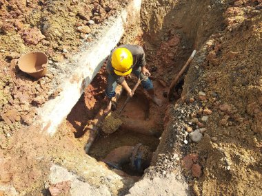 Kuala Lumpur, Malezya -12 Nisan 2019: Şantiyedeki siperlerde yeraltı hizmet borusunu tamir eden inşaat işçileri.     