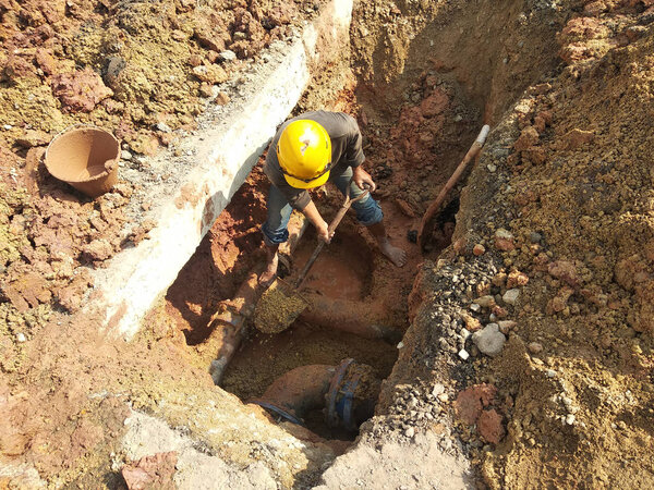 KUALA LUMPUR, MALAYSIA-APRIL 12, 2019: Строители ремонтируют подземные трубы коммунальных услуг в траншеях на строительной площадке
.     