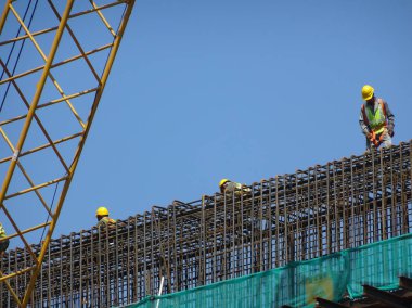 Kuala Lumpur, Malezya -03 Şubat 2017: Şantiyede yüksekte çalışan inşaat işçileri. Başlarına kötü bir şey gelmesini önlemek için uygun güvenlik donanımı takmaları istenir.. 