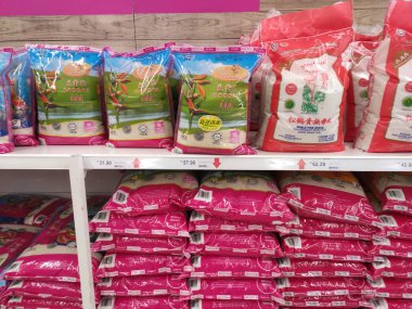 Kuala Lumpur, Malezya -2 Eylül 2018: Plastik ambalajdaki pirinç, satışa sunulan süpermarketin rafına yığılmış. Türü ve fiyatının çeşitliliği