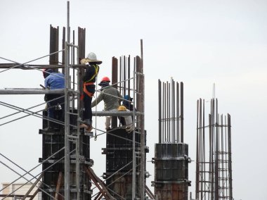 Kuala Lumpur, Malezya -30 Eylül 2016: İnşaat işçileri şantiyede çelik betonarme kolonu imal etti. Kereste ve metali kalıp olarak kullanıyorlar.. 