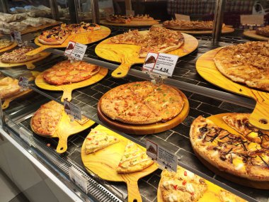 Kuala Lumpur, Malezya -16 Temmuz 2019: Sıcak pizzalar, alışveriş merkezindeki cam ısıtıcının içinde satışa sunulan rafta sergileniyor. Çeşitli tip pizzalar müşterilere sunulmaktadır.