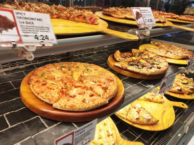 Kuala Lumpur, Malezya -16 Temmuz 2019: Sıcak pizzalar, alışveriş merkezindeki cam ısıtıcının içinde satışa sunulan rafta sergileniyor. Çeşitli tip pizzalar müşterilere sunulmaktadır.