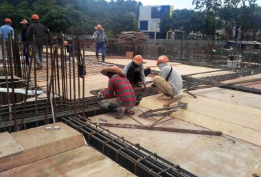 Kuala Lumpur, Malezya -31 Ağustos 2017: İnşaat işçileri şantiyede çelik takviye çubuğu imal ediyor. Takviye çubuğu küçük tel kullanılarak birbirine bağlandı..  