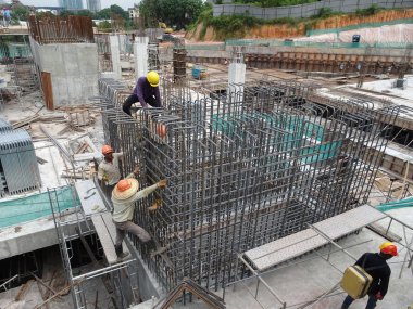 Kuala Lumpur, Malezya -31 Ağustos 2017: İnşaat işçileri şantiyede çelik takviye çubuğu imal ediyor. Takviye çubuğu küçük tel kullanılarak birbirine bağlandı..  