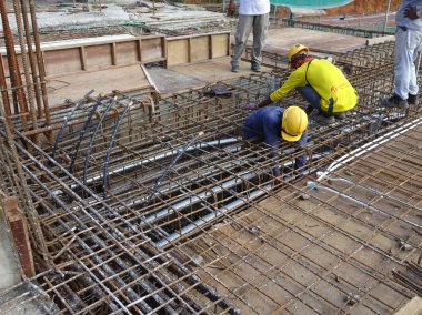 Kuala Lumpur, Malezya -31 Ağustos 2017: İnşaat işçileri şantiyede çelik takviye çubuğu imal ediyor. Takviye çubuğu küçük tel kullanılarak birbirine bağlandı..  