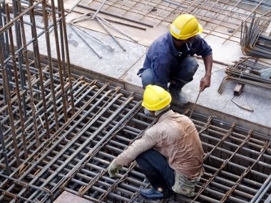 Kuala Lumpur, Malezya -31 Ağustos 2017: İnşaat işçileri şantiyede çelik takviye çubuğu imal ediyor. Takviye çubuğu küçük tel kullanılarak birbirine bağlandı..  