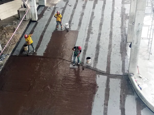 Kuala Lumpur, Malezya -25 Temmuz 2018: Beton levhaüzerine inşaat işçileri tarafından uygulanan su yalıtım membranı. Suyun beton levhanın altına girmesini önlemek için su yalıtım tabakası. 