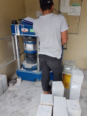 Kuala Lumpur, Malezya -20 Haziran 2017: Laboratuvarda sıkıştırma makinesi kullanılarak beton küp mukavemet sıkıştırma testi. Sonucu kaydetmeyi yürüten yetenekli laboratuvar personeli. 