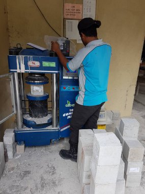 Kuala Lumpur, Malezya -20 Haziran 2017: Laboratuvarda sıkıştırma makinesi kullanılarak beton küp mukavemet sıkıştırma testi. Sonucu kaydetmeyi yürüten yetenekli laboratuvar personeli. 