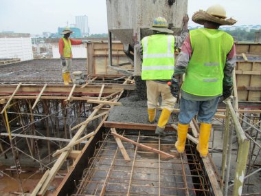 Kuala Lumpur, Malezya -31 Ocak 2017: İnşaat işçileri, mobil vinçten beton kovakullanarak şantiyede zemin levha sıyrıklarına ıslak beton döküyor.  