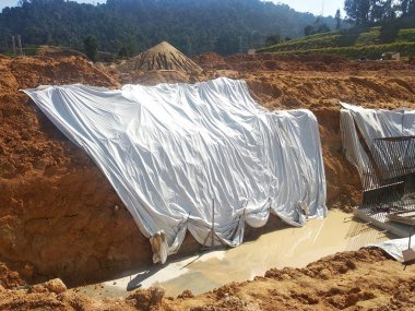 Seremban, Malezya -18 Ağustos 2019: Yağmur suyu ile toprak erozyonunu önlemek için plastik levhalar kullanılarak inşaat sırasında geçici eğim koruması. Çalışma tamamlandıktan sonra koruma kaldırılacak.  