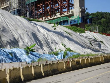 Seremban, Malezya -18 Ağustos 2019: Yağmur suyu ile toprak erozyonunu önlemek için plastik levhalar kullanılarak inşaat sırasında geçici eğim koruması. Çalışma tamamlandıktan sonra koruma kaldırılacak.  