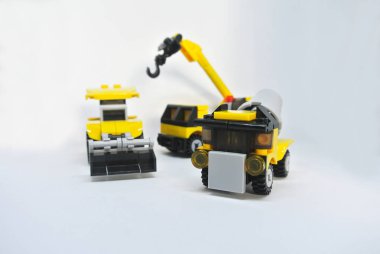 Beyaz bir arka plan üzerinde izole plastik bloklardan yapılmış üç inşaat ağır makine oyuncakları. 