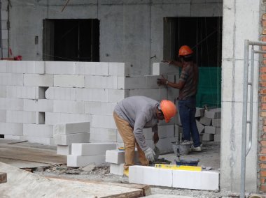 Kuala Lumpur, Malezya -04 Mart 2017: İnşaat işçileri şantiyede duvar haline hafif blok tuğla lar döşeyerek. Blok özel yapıştırıcı kullanılarak birlikte bağ oldu. 