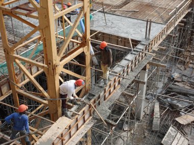 Kuala Lumpur, Malezya - 27 Nisan 2017: İnşaat işçilerinden oluşan bir grup, beton pompadaki beton hortumu kullanarak inşaat alanındaki kereste biçimine döküyorlar..  
