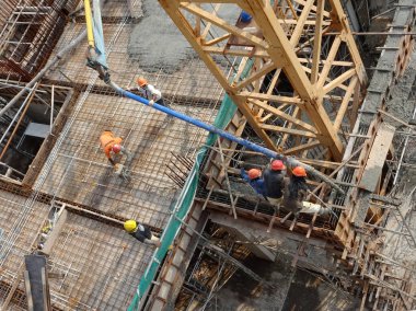 Kuala Lumpur, Malezya - 27 Nisan 2017: İnşaat işçilerinden oluşan bir grup, beton pompadaki beton hortumu kullanarak inşaat alanındaki kereste biçimine döküyorlar..  