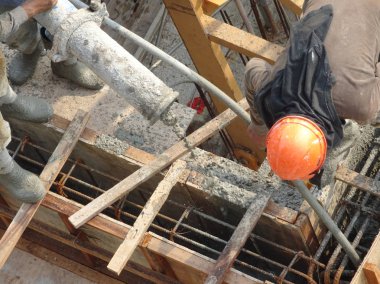 Kuala Lumpur, Malezya - 27 Nisan 2017: İnşaat işçilerinden oluşan bir grup, beton pompadaki beton hortumu kullanarak inşaat alanındaki kereste biçimine döküyorlar..  