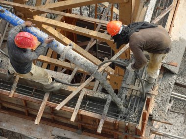 Kuala Lumpur, Malezya - 27 Nisan 2017: İnşaat işçilerinden oluşan bir grup, beton pompadaki beton hortumu kullanarak inşaat alanındaki kereste biçimine döküyorlar..  