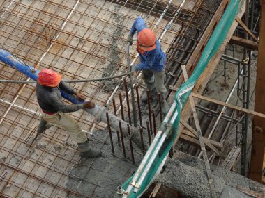 Kuala Lumpur, Malezya - 27 Nisan 2017: İnşaat işçilerinden oluşan bir grup, beton pompadaki beton hortumu kullanarak inşaat alanındaki kereste biçimine döküyorlar..  