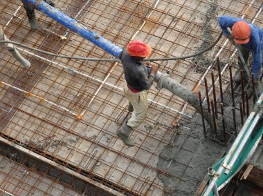 Kuala Lumpur, Malezya - 27 Nisan 2017: İnşaat işçilerinden oluşan bir grup, beton pompadaki beton hortumu kullanarak inşaat alanındaki kereste biçimine döküyorlar..  