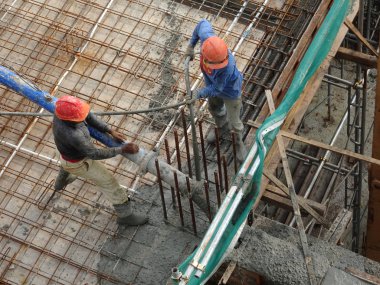 Kuala Lumpur, Malezya - 27 Nisan 2017: İnşaat işçilerinden oluşan bir grup, beton pompadaki beton hortumu kullanarak inşaat alanındaki kereste biçimine döküyorlar..  