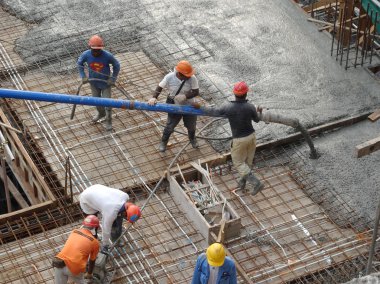 Kuala Lumpur, Malezya - 27 Nisan 2017: İnşaat işçilerinden oluşan bir grup, beton pompadaki beton hortumu kullanarak inşaat alanındaki kereste biçimine döküyorlar..  